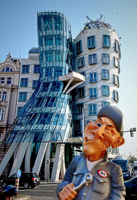 figurine of a funny mechanic on the background of a crooked house