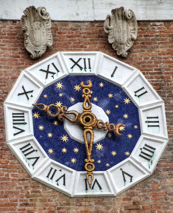 antique clock with golden arrows on the wall of the building