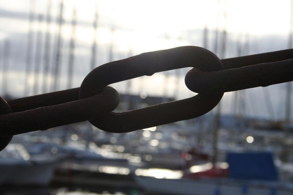 Close-up of the metal chain at background with sailing boats in light