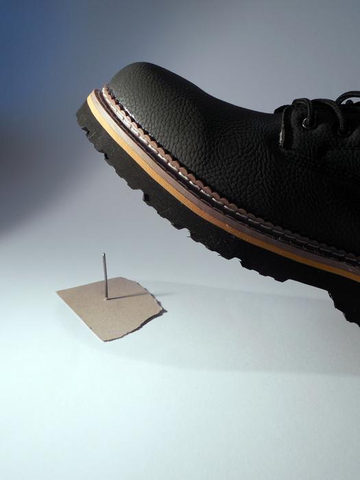 Close-up of the black shoe, in light, above the nail