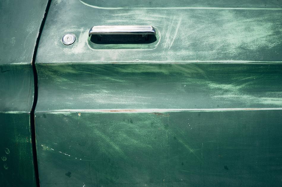 Close-up of the green door of a truck, with the traces