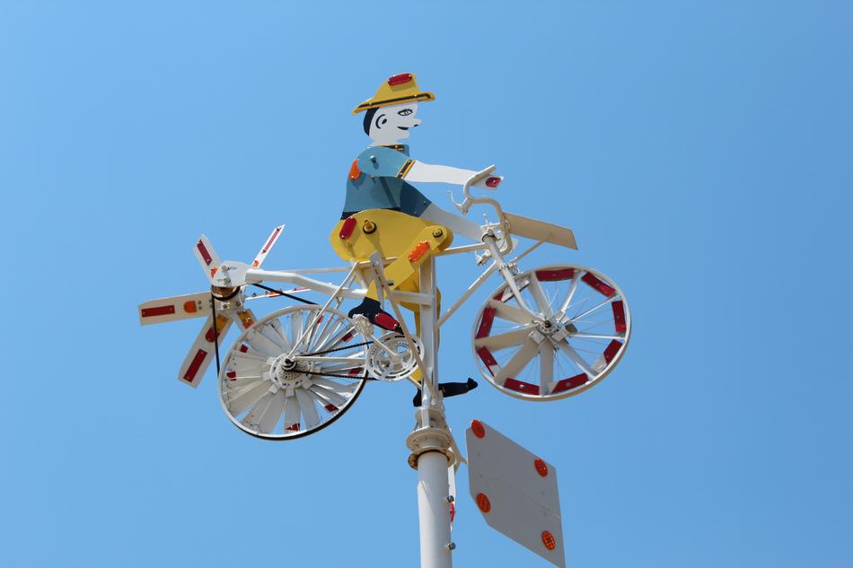 Colorful whirligig with the man on bike, at blue sky on background