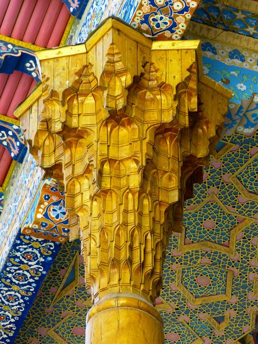 Beautiful, yellow, carved wood pill, at background with pattern in the mosque in Bukhara, Uzbekisan
