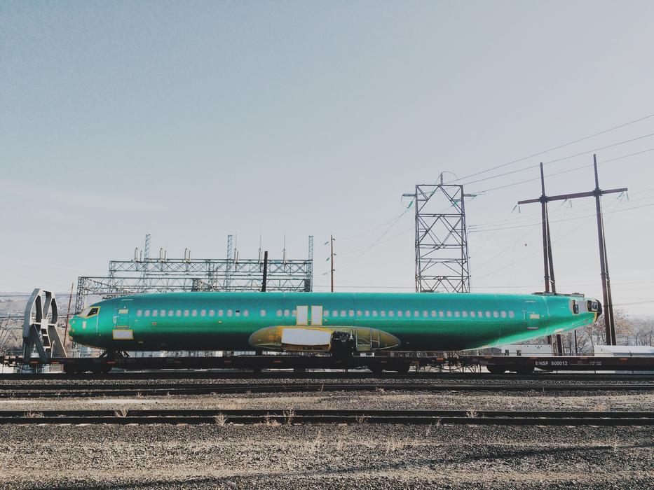 Glossy, turquoise airplane, near the power lines, on the landscape
