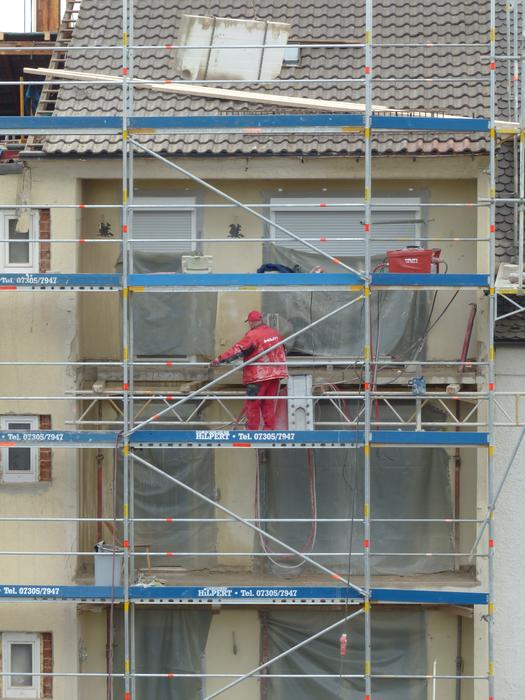 Person on the blue scaffold of the house