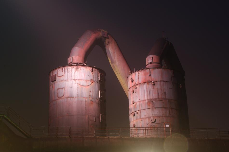 two huge industrial tanks with pipes at night