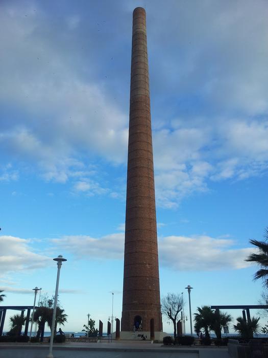 Industrial fireplace, among the trees, at blue sky with clouds on background