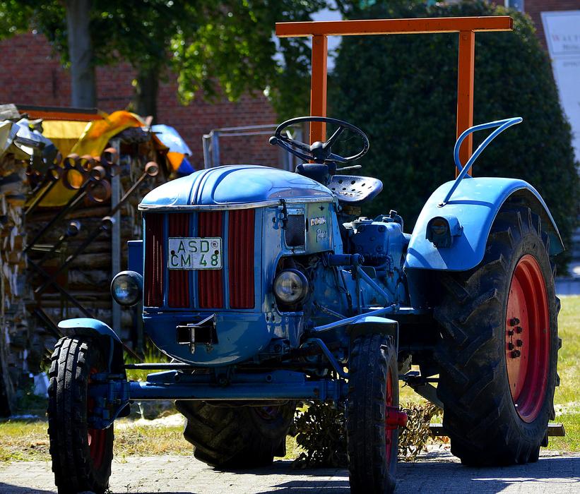 Close-up of the blue 'Hanomag' tractor with black and red wheels, in light