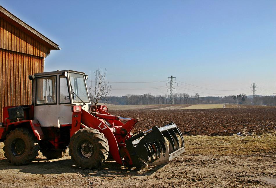 Tractor, near the wooden house, on the colorful and beautiful fields with electricity towers
