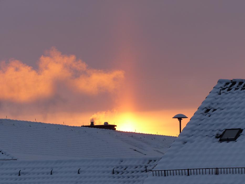 sunbeams over snow-capped rooftops at dusk
