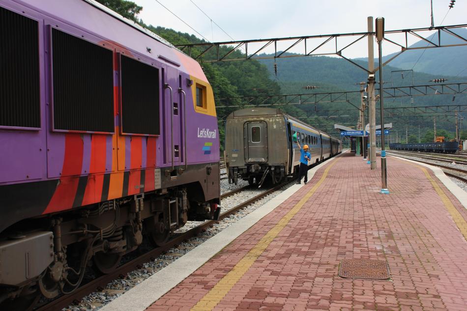 Person, near the colorful train on the railway in the Republic of Korea, among the beautiful, green mountains