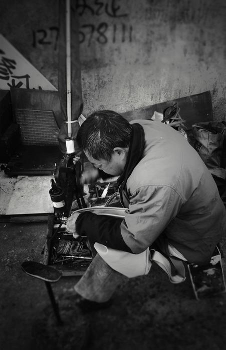 man stitching backpack by sewing machine