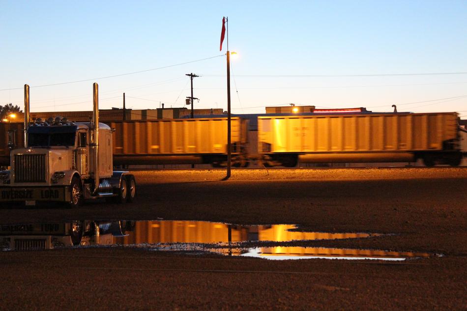 Heavy truck in view of speeding Train at dusk