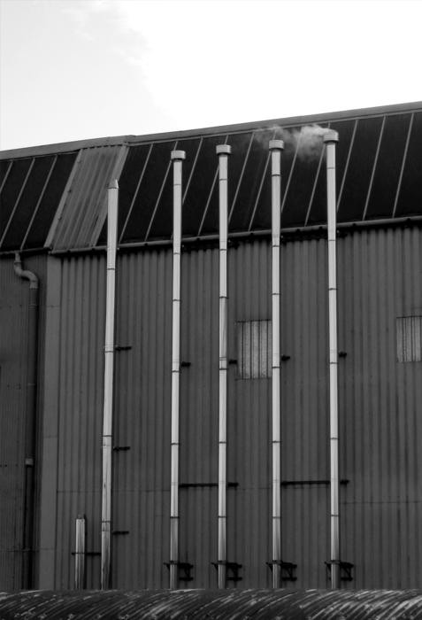Industrial factory with shiny flues, under the sky with clouds