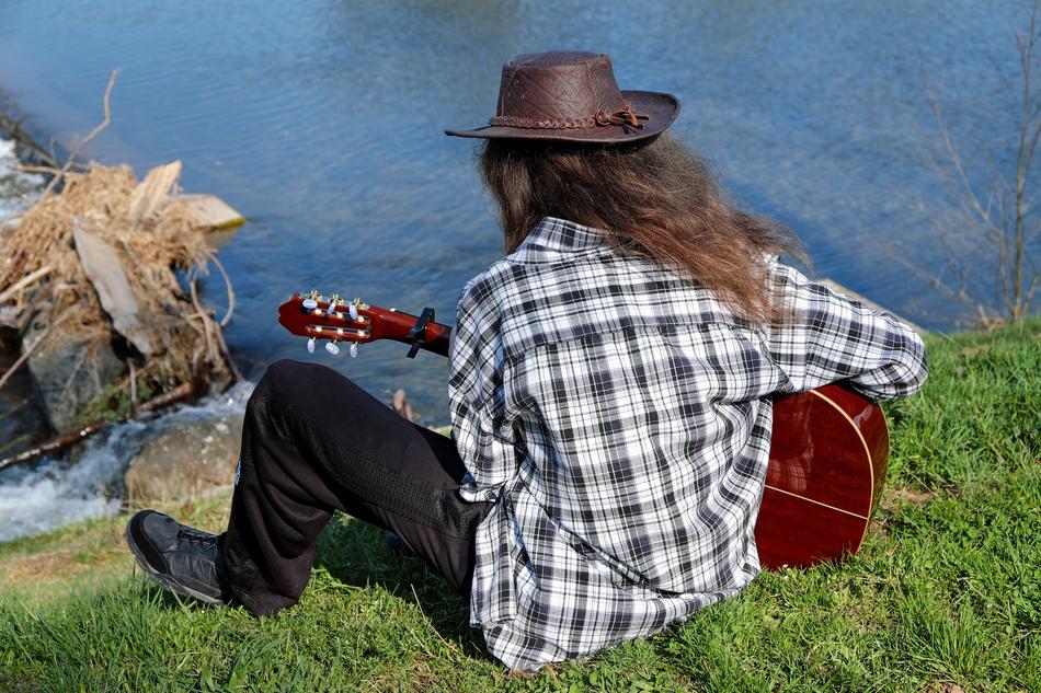 guitarist on the grass above the water