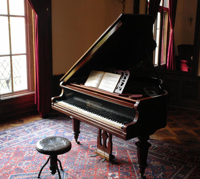 Beautiful, classical, wooden piano and chair on the colorful, patterned carpet