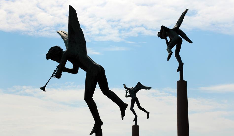 Beautiful statues of the angels, at background with blue sky with white clouds