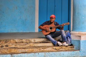 man playing guitar while sitting on the stairs