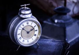 Shiny, retro clock, with the metallic cover, among the darkness