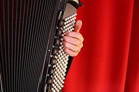 Person, playing on the beautiful accordion at background with red curtain