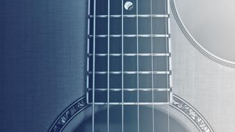 Black and white photo of the close-up of the beautiful, wooden guitar with metal strings and ornament in light
