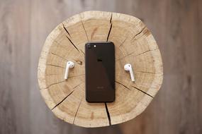smartphone and headphones lie on a stump