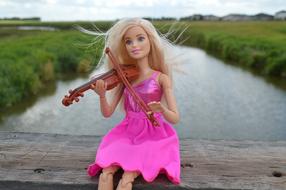 barbie doll with a violin near the river