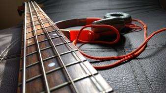 Headphones and neck of guitar on black leather