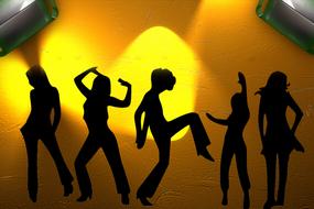 Black silhouettes of the dancing people, at beautiful background with yellow and orange light