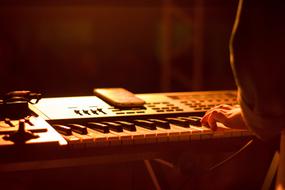 Person playing on the electric piano in beautiful, orange light