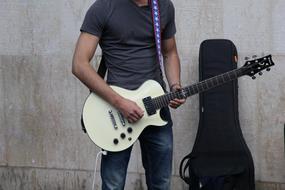 African Man plays electric Guitar at wall