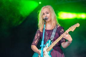 girl musician with a guitar on stage