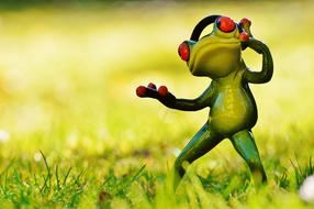 Green ceramic frog with headphones on the lawn