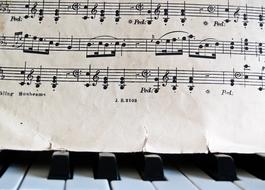 worn music sheet over Piano keys