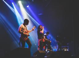 a group of musicians on stage under the light of spotlights