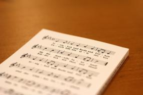 White and black music sheet with the notes of the National Anthem of Germany, on the wooden surface