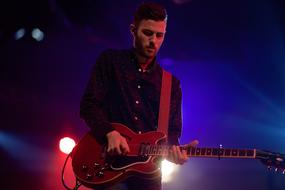 Musician playing electric guitar on the stage with colorful lights