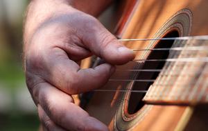 macro photo of a manâs fingers on the strings of a guitar