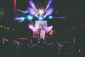 young male Singer on stage in front of crowd at night