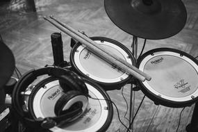 wooden sticks and headphones lie on a drum kit