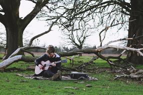 Man playing guitar under the trees