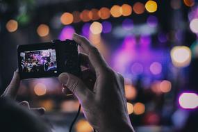 Person filming the concert on the beautiful stage with colorful lights
