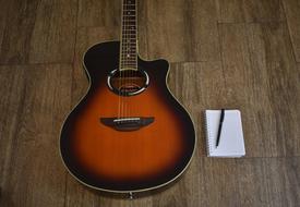 Songwriting, pen on notebook near guitar