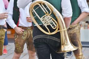 Man in traditional Bavarian costume with brass instrument on back