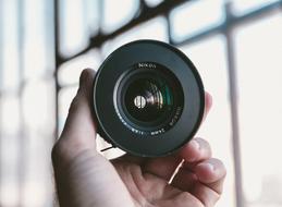 Close-up of the beautiful, shiny, colorful camera lens on the hand