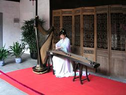 Asian girl, playing on the musical instrument, near the green plants, in China