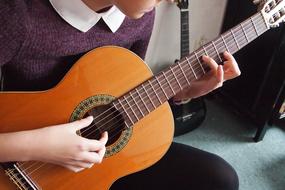 young girl learning to play guitar