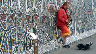 Street jazz musician near the colorful graffiti wall