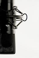 Close-up of the shiny, black studio microphone, with the stand, at white background