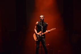 singer with a guitar on stage in the spotlight